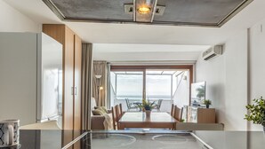 Een moderne keuken met een centraal eiland, een eetgedeelte met uitzicht en een woonruimte met televisie en airconditioning.