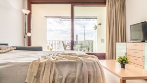 Une chambre d’hôtel avec un lit, un bureau, une télévision et un balcon donnant sur la plage.