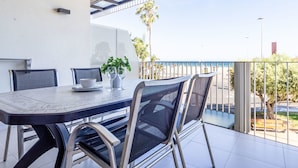 Un espace repas extérieur moderne, avec une table et des chaises, une plante en pot et une vue sur la plage.
