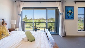 A hotel room with a large bed, a view of the outdoors, a painting on the wall, and a balcony with chairs. - Lux Clyde North Super Spacious Retreat (Clyde North)