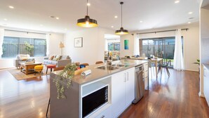A modern kitchen with a central island, stainless steel appliances, and pendant lighting. - Lux Clyde North Super Spacious Retreat (Clyde North)