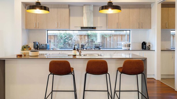 A modern kitchen with a large island, pendant lights, and a view of the outdoors. - Lux Clyde North Super Spacious Retreat (Clyde North)