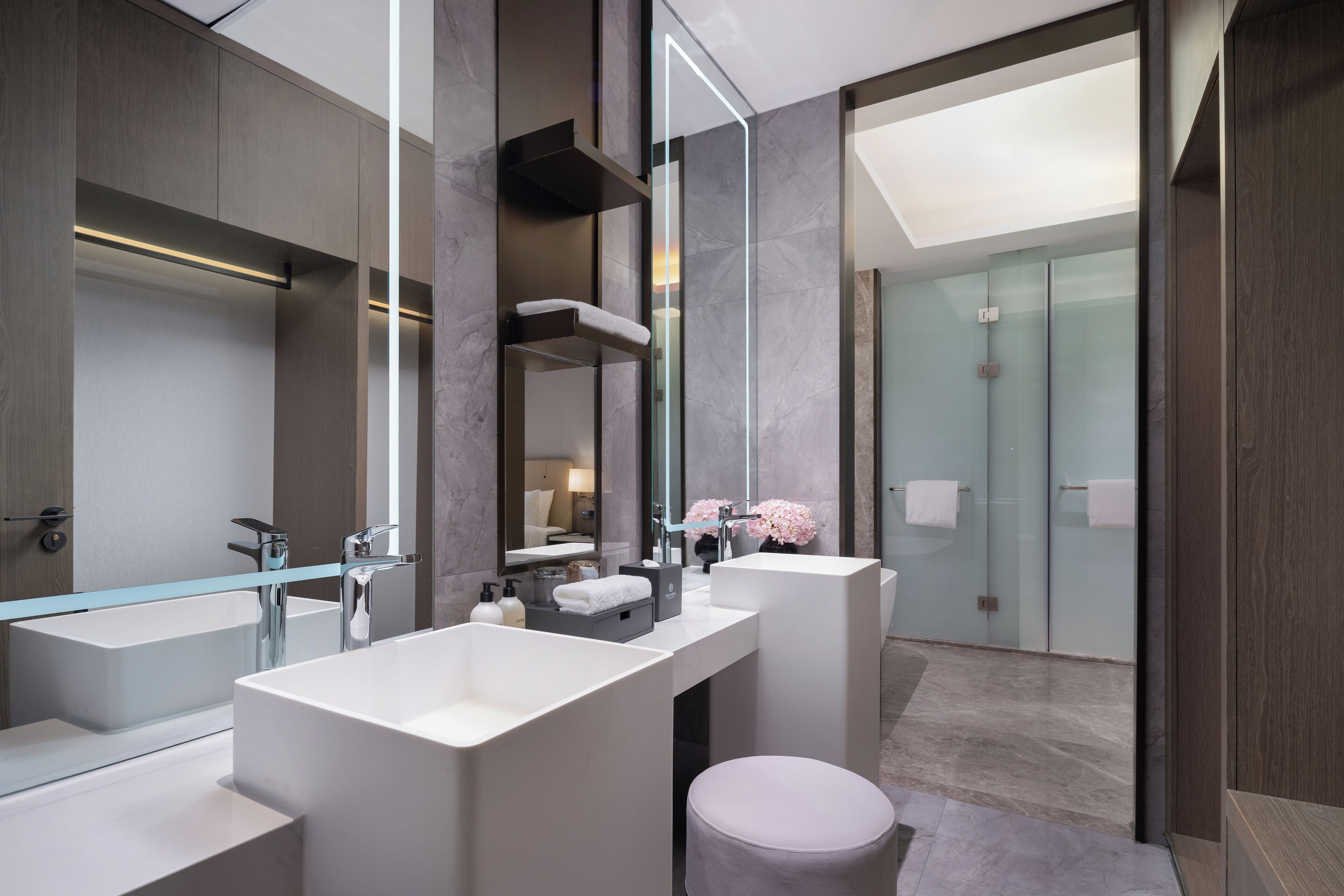 A modern bathroom with two large sinks, a glass shower enclosure, and a vanity with a mirror.