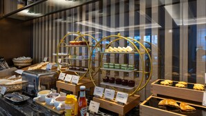 A buffet with various food items, including pastries and desserts, displayed on wooden stands and glass cases. - EDDRER HOTEL (Shenzhen)