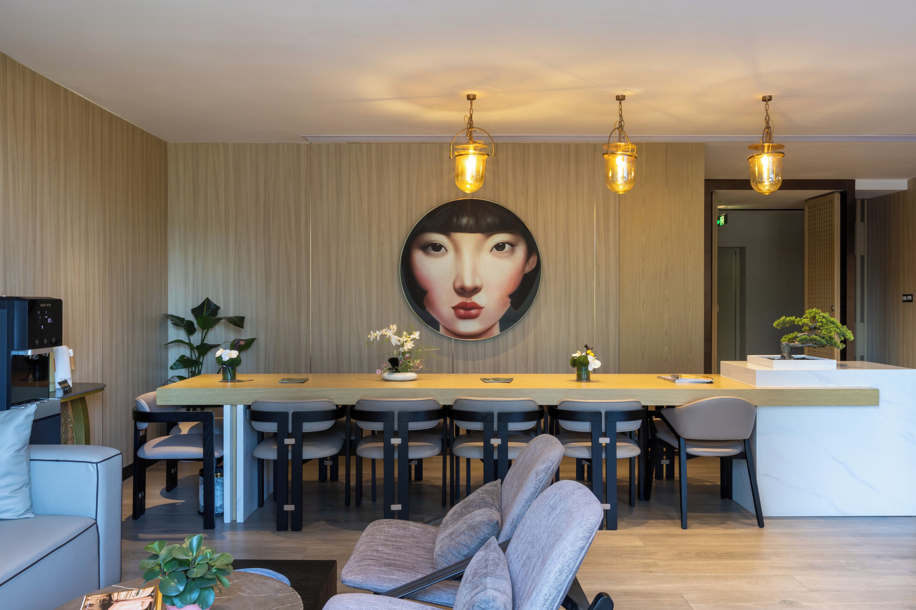 A modern hotel lobby with a long reception desk, multiple seating areas, and a large wall art piece.
