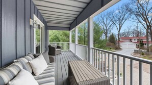 En overdækket veranda med en sofa og et bord, der udover et boligområde.