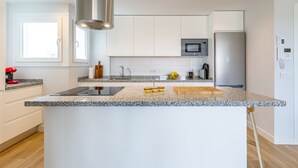 Eine moderne Küche mit weißen Schränken, Granit-Arbeitsplatten, einer Edelstahl-Dunstabzugshaube, einer integrierten Mikrowelle und einem Kühlschrank.