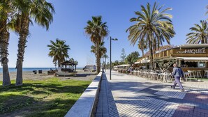Un paseo marítimo con palmeras, una playa y un restaurante llamado 'Casa Miguel'.