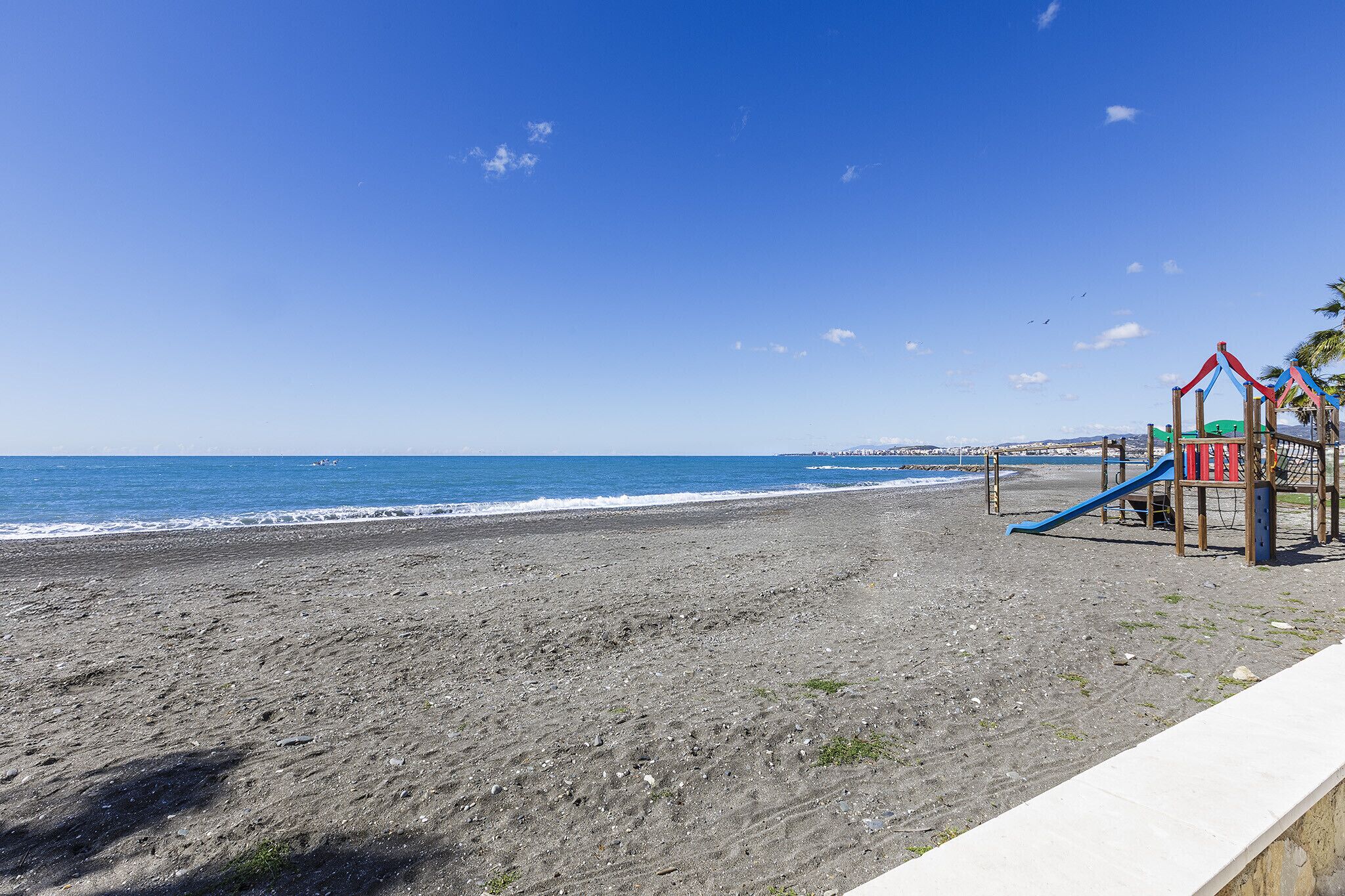 Una spiaggia con un'area giochi e vista sull'oceano.