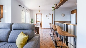 A living room with a grey sofa, a yellow pillow, and a dining area with a bar.