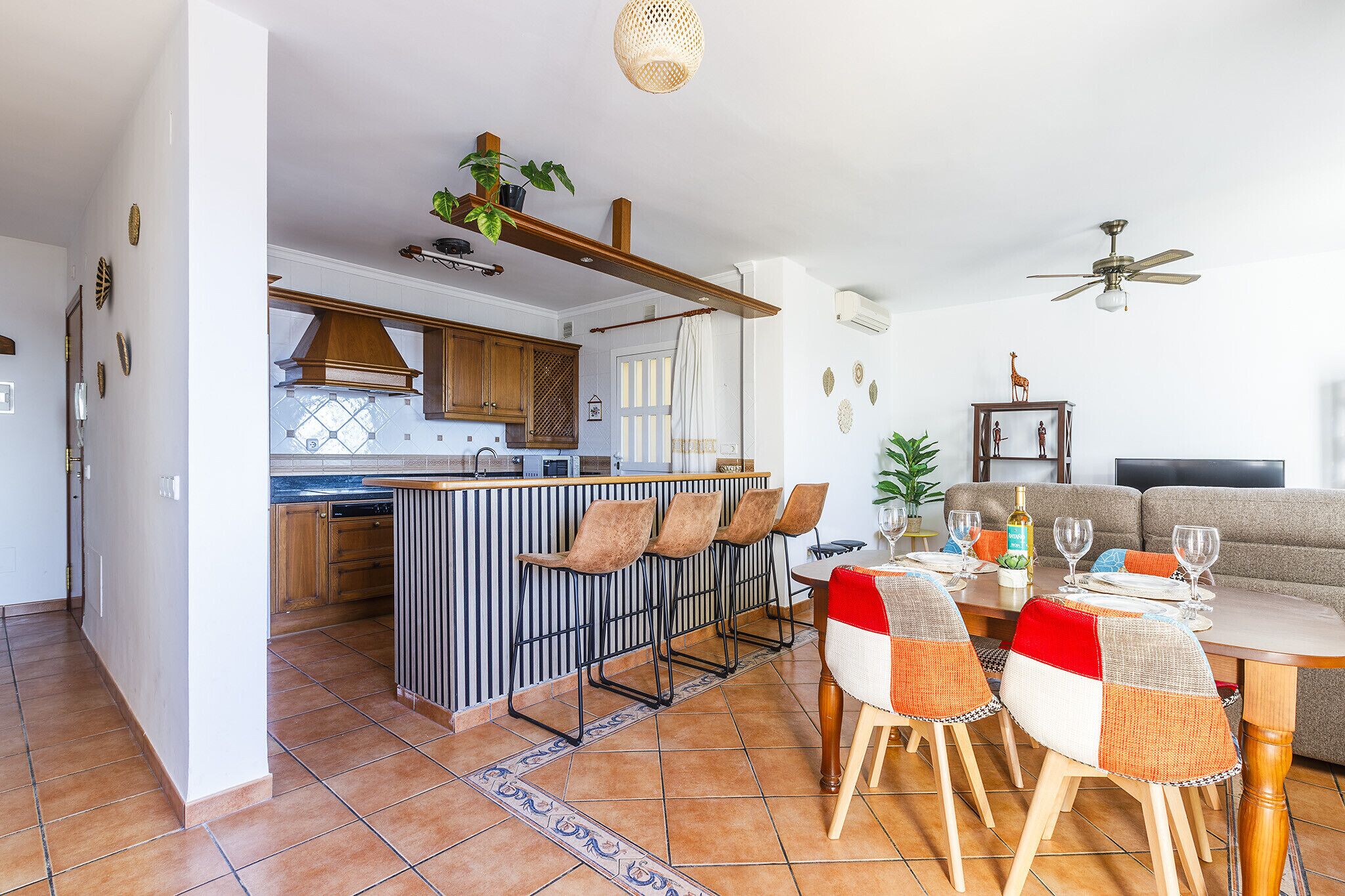 A modern kitchen with a central island, bar stools, and a dining area with a table and chairs.
