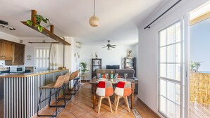 A modern kitchen with a bar area, dining table with chairs, and a large window with a view.