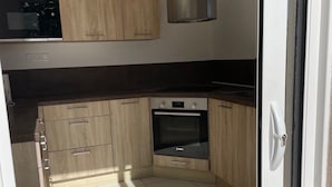 Eine moderne Küche mit Holzausstattung, einem Backofen von Bosch und einer schwarzen Arbeitsplatte.