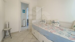 A bedroom with a bed, a small table, and a radiator. - APPARTAMENTO VIA DEL MARE 20 - VIA DEL MARE 20 (Marciana)
