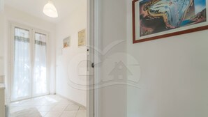 A hallway with a tiled floor, a door with a circular handle, and a painting on the wall. - APPARTAMENTO VIA DEL MARE 20 - VIA DEL MARE 20 (Marciana)