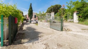 A gated residential area with a paved driveway leading to a house. - APPARTAMENTO VIA DEL MARE 20 - VIA DEL MARE 20 (Marciana)