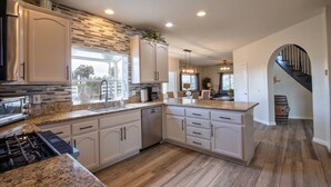 A modern kitchen with granite countertops, white cabinetry, and a built-in stove. - Book Your Stay at Casa da Saudade | Pool, Slide, & Wine Country Views (Temecula)