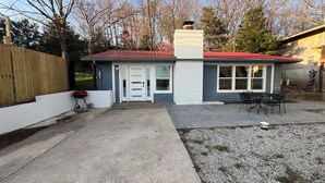A small, single-story house with a red roof, a white door, and a brick chimney. - Peaceful Lakefront Cabin (Lincoln)