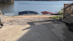 A lakeside view with a concrete deck, two covered areas, and a wooden staircase. - Peaceful Lakefront Cabin (Lincoln)