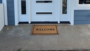 A white front door with a welcome mat, a small window, and a mailbox. - Peaceful Lakefront Cabin (Lincoln)