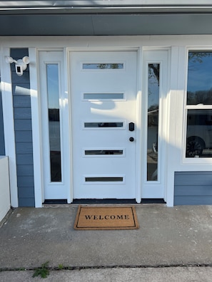 Welcome to this charming home, featuring a glass panel door and a black doorbell.