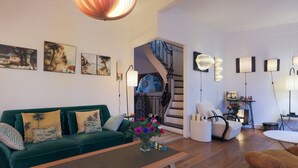 Un salon avec un canapé vert, une table basse et un escalier menant à un autre niveau.