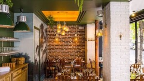 Un restaurant aux murs de briques, aux tables en bois et aux lampes suspendues.