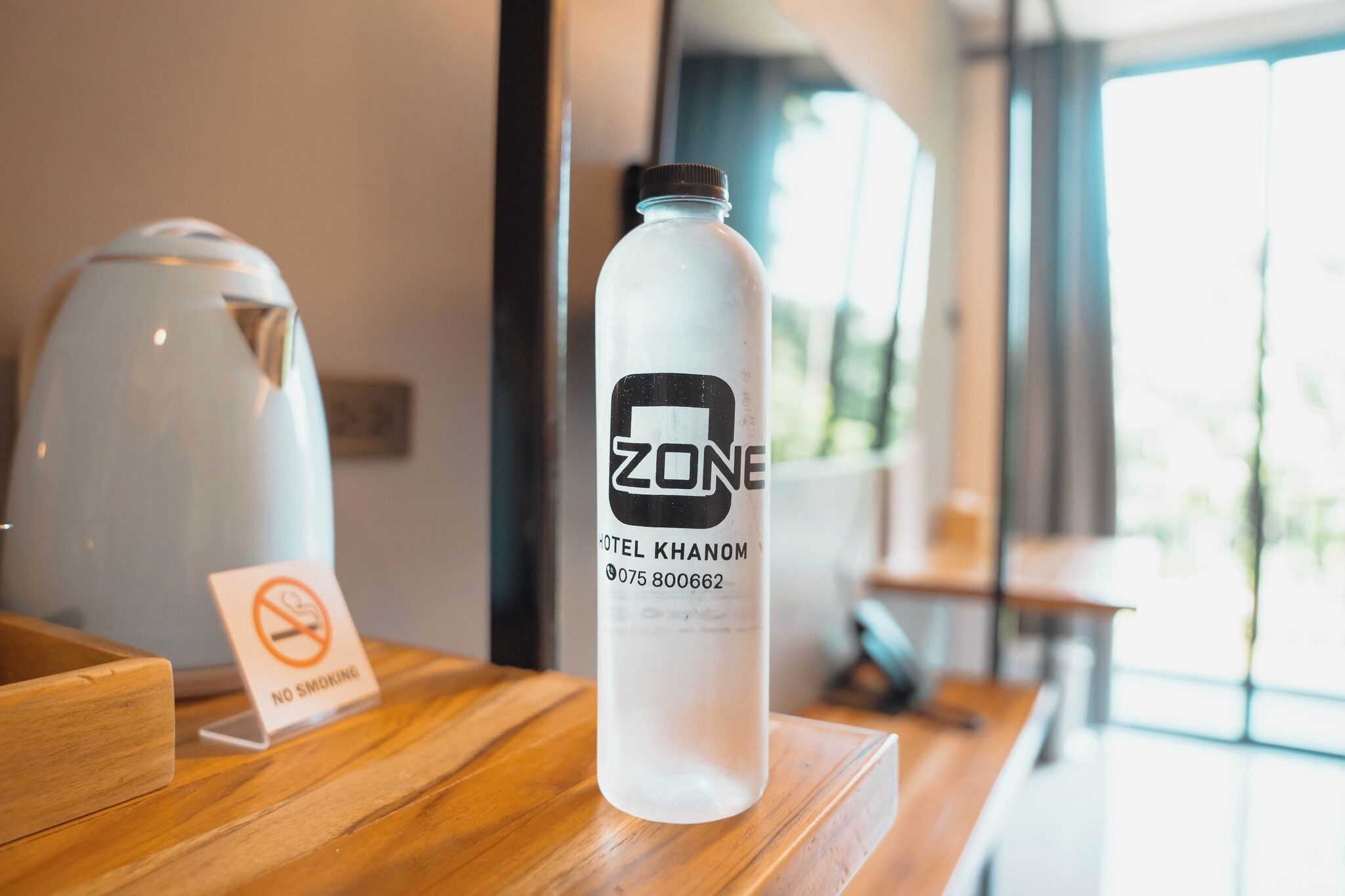 A hotel water bottle with a label on a wooden table.