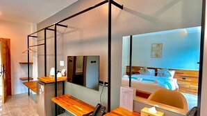 A modern hotel room with a wooden desk, a chair, a bed with a view, and a mirror reflecting the room. - Ozone hotel khhanom (Khanom)