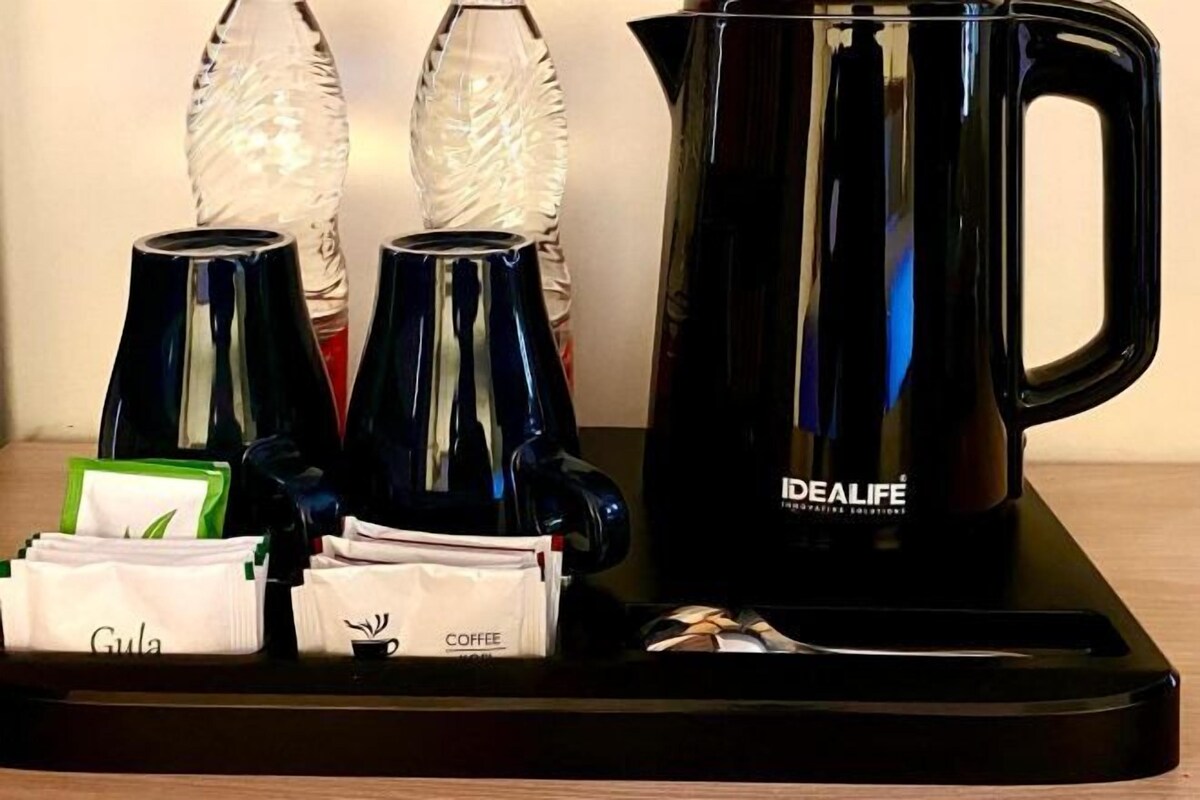 A coffee station with a black coffee pot, two glass carafes, and coffee pods labeled "Gula" and "Coffee."