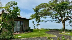 A house with a garden, a gravel path, and a large tree. - Tebing View Glamping, Azana Hotel Collection (Parongpong)