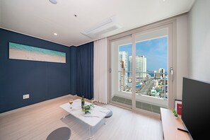 Un salon moderne avec vue sur la ville, un téléviseur à écran plat et un coin repas comprenant une table et des chaises.