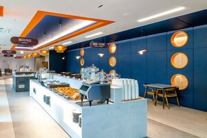 Un moderno comedor para el desayuno con barra libre, que incluye una cafetera y diferentes opciones de comida.