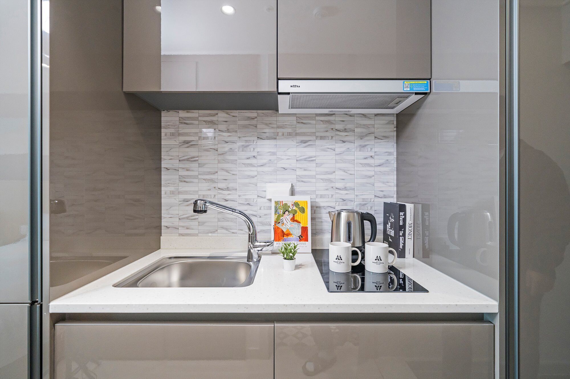A modern kitchen with a stainless steel sink, a kettle, and a coffee maker on the countertop.