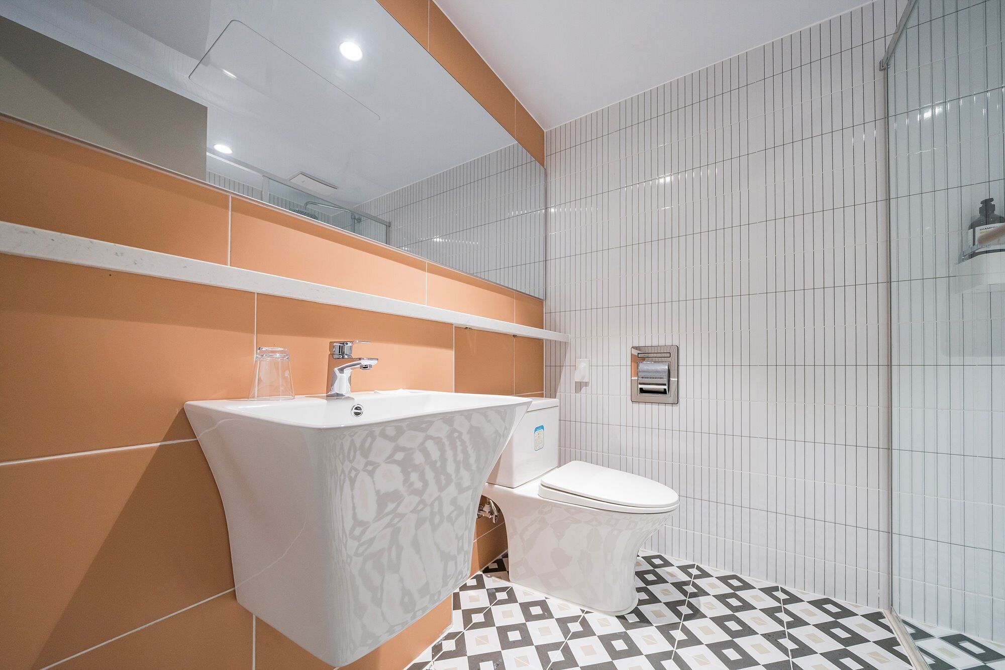 Et moderne badeværelse med en hvid vask, et toilet og et gulv med et mønster.