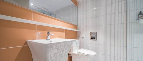 Et moderne badeværelse med en hvid vask, et toilet og et gulv med et mønster.