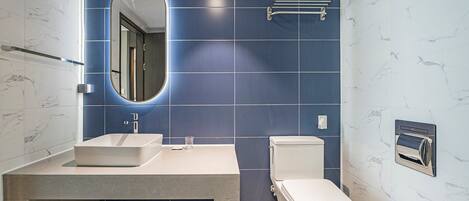 A bathroom with a white sink, a toilet, and a mirror.