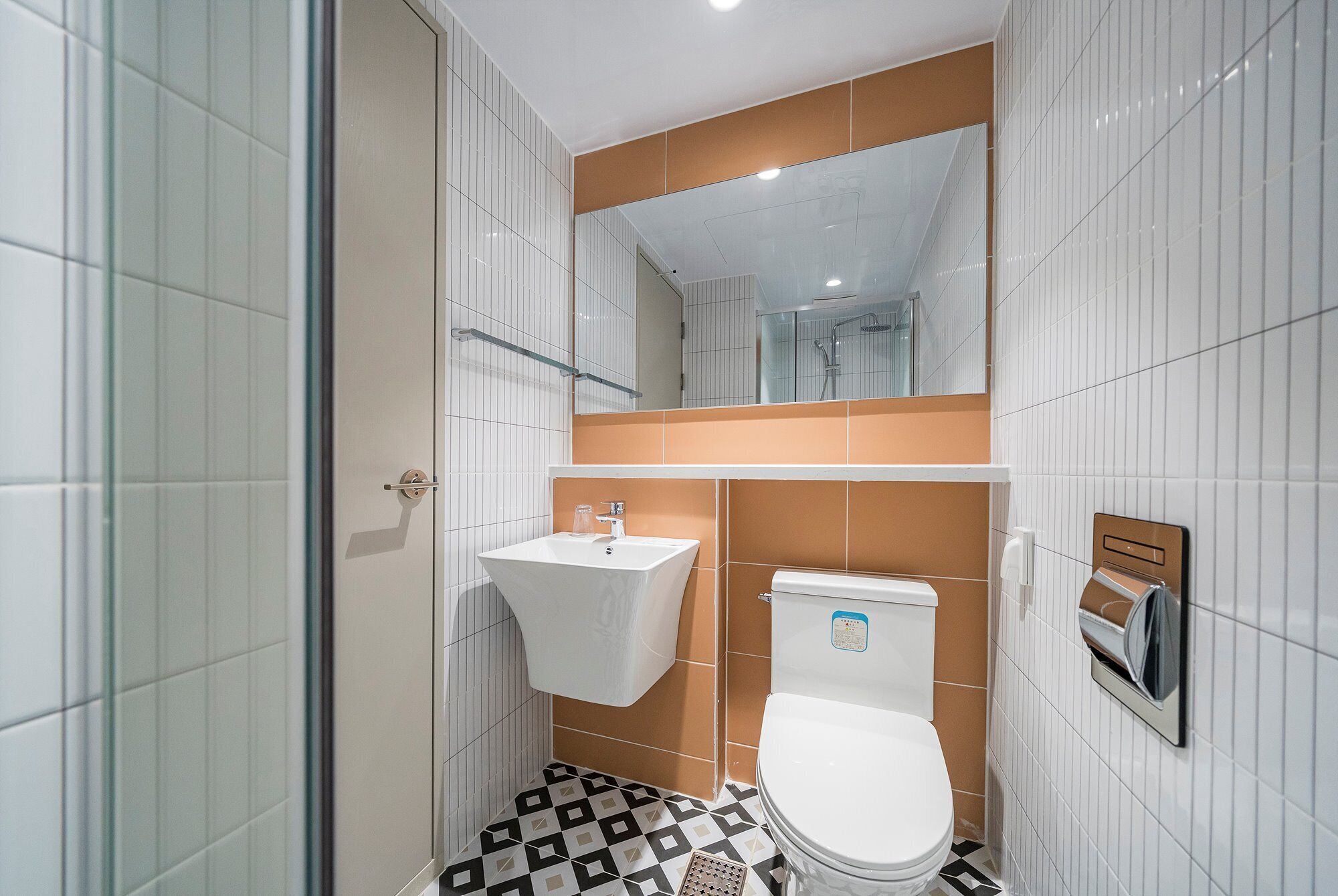 Un baño con inodoro blanco, lavamanos y zona de ducha.