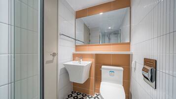 Un baño con inodoro blanco, lavamanos y zona de ducha.