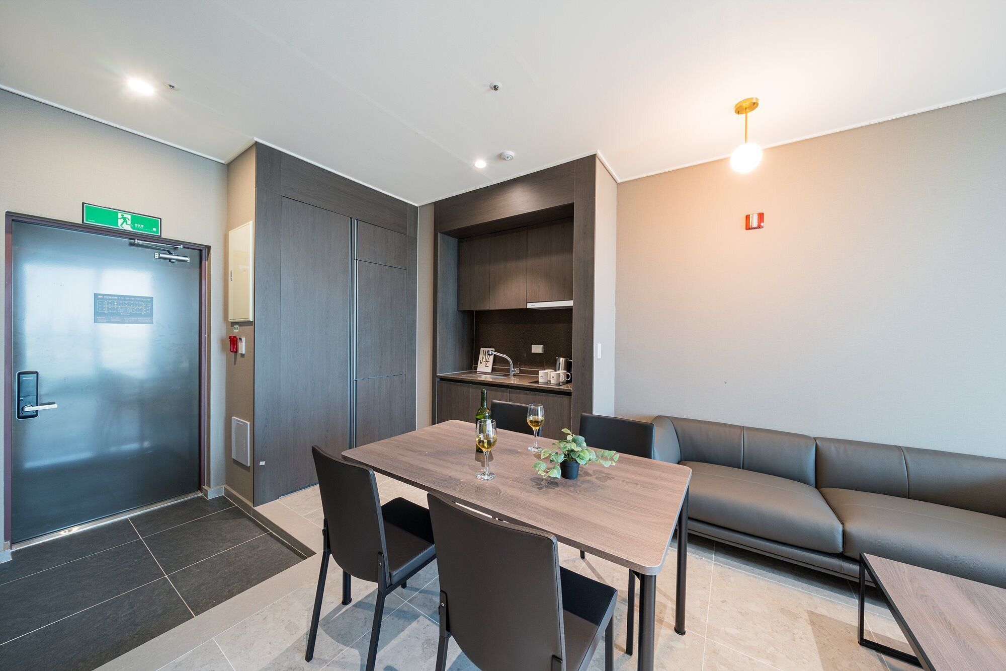 A modern hotel room with a dining area, a sofa, and a kitchenette.