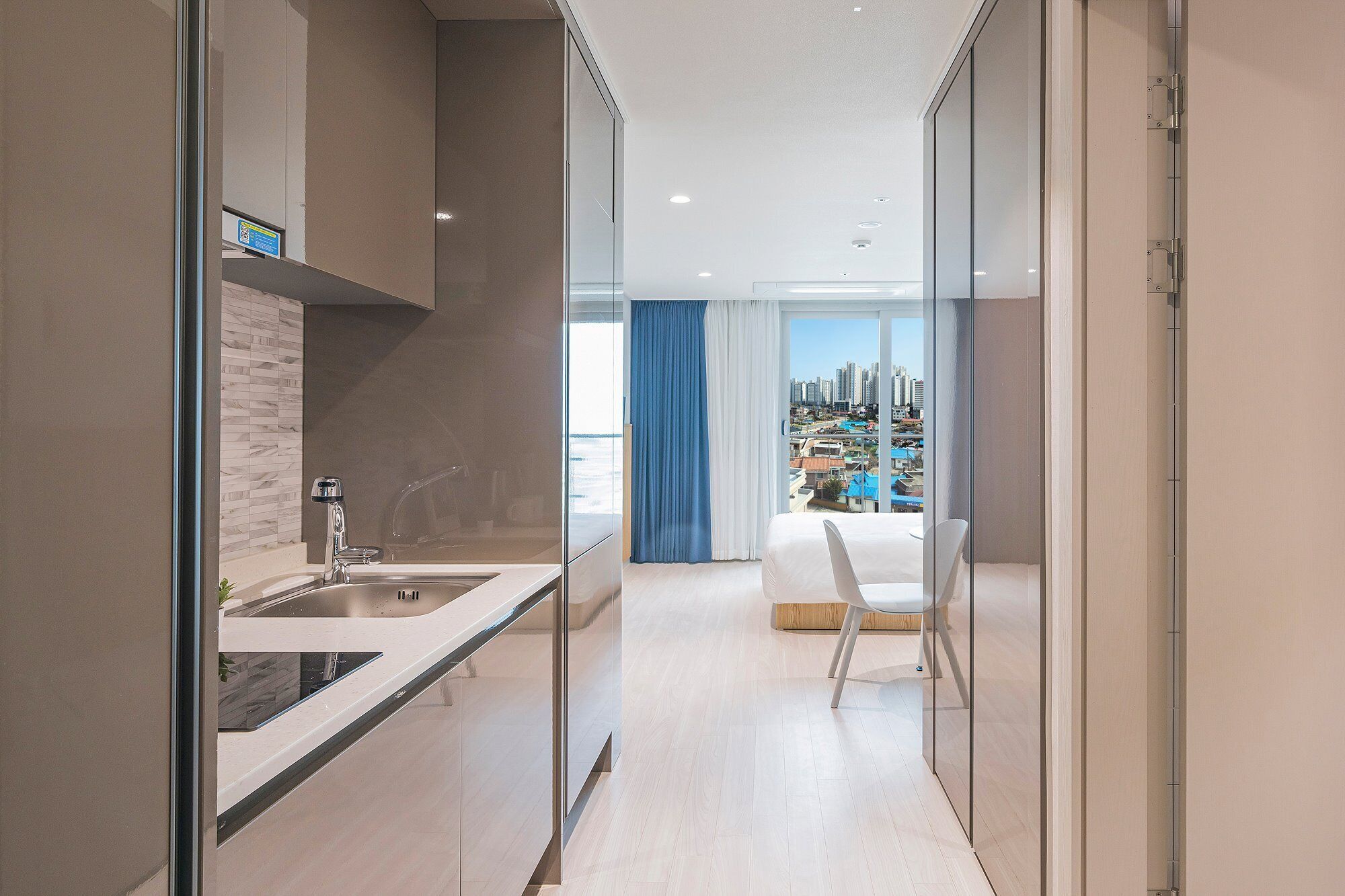 Una cocina moderna con un lavamanos y vistas a un paisaje urbano a través de grandes ventanales.