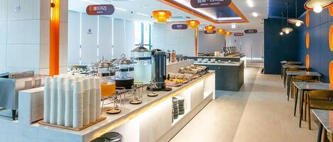 A modern breakfast area with a buffet setup, including plates, bowls, and a coffee station.