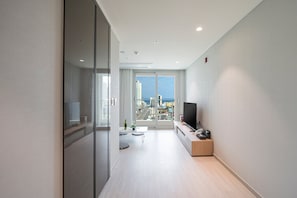 Un appartement moderne doté d’une grande fenêtre, d’un téléviseur à écran plat et d’un design minimaliste.