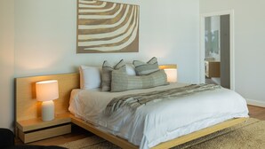 Une chambre à coucher moderne avec un cadre de lit en bois, une literie blanche et deux lampes de chevet.