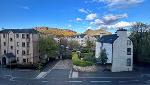 A street view with buildings, a mountain in the background, and a clear sky. - Edinburgh’s Arthur’s Seat View (Edinburgh)