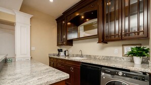 Una cocina con encimeras de granito, armarios de madera, lavavajillas y lavadora y secadora integradas.