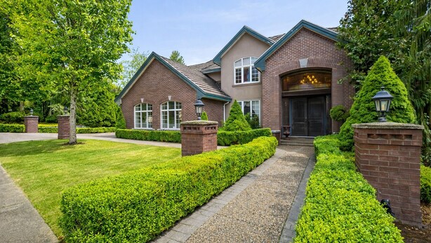 A two-story house with a brick exterior, a front porch, and a well-maintained lawn.