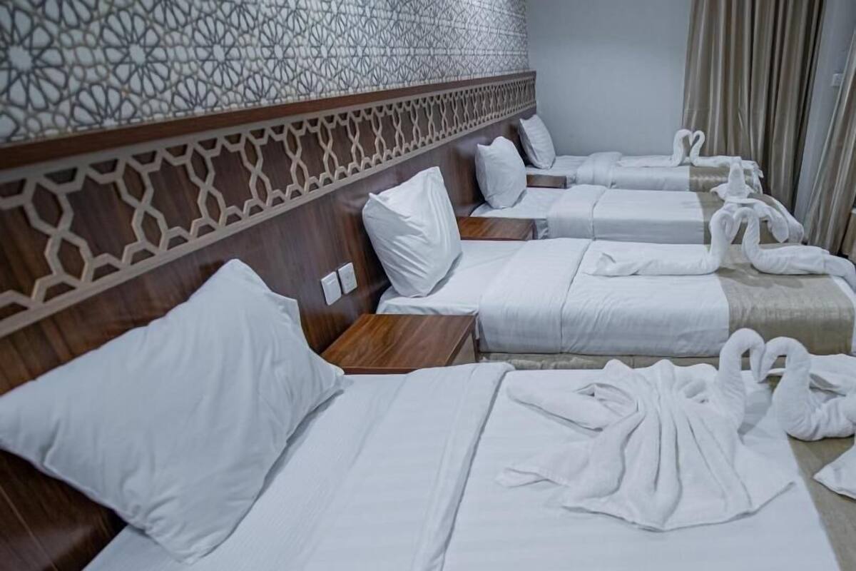 Ein Hotelzimmer mit drei Betten, jeweils mit weißen Leinen und Kissen.