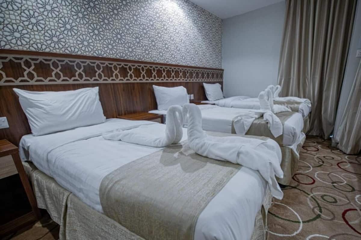Ein Hotelzimmer mit zwei Betten, einer Wandverzierung und einem gemusterten Teppich.