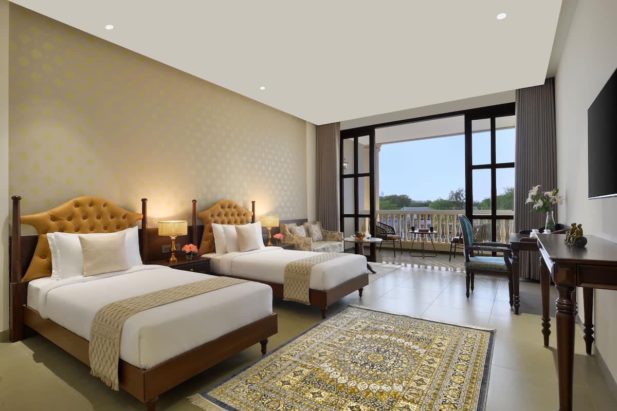A hotel room with two beds, a large window, a balcony, and a view of the outdoors.